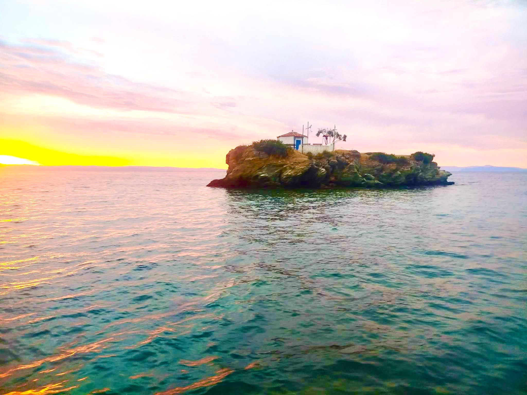 Sunset over a small island chapel in the Aegean Sea